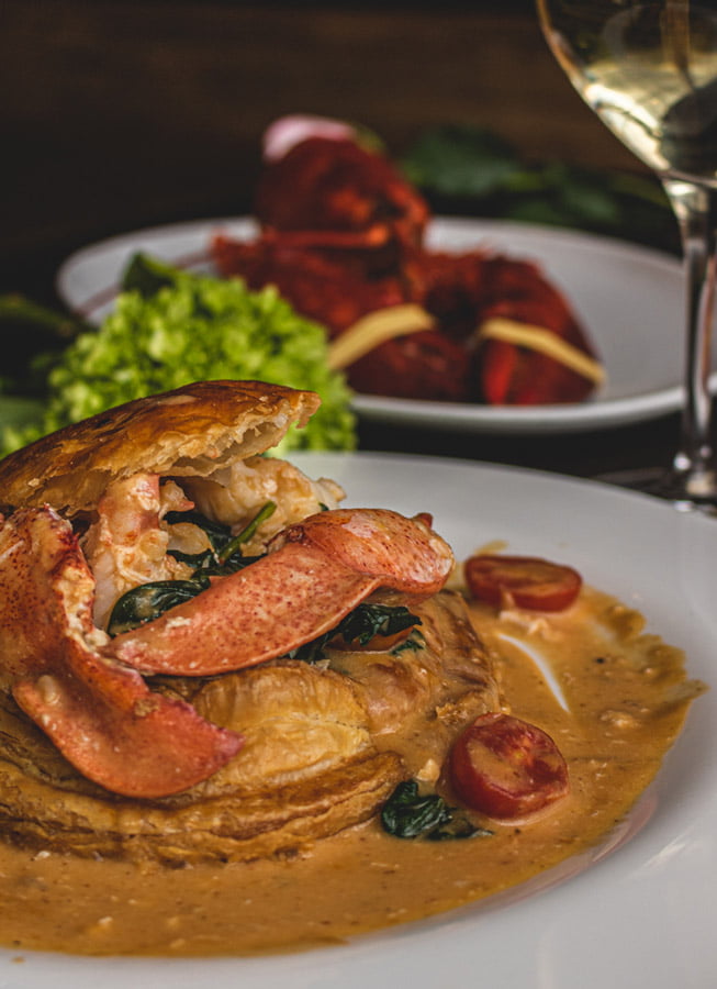 Image of Lobster Newburgh with a whole lobster and glass of white wine