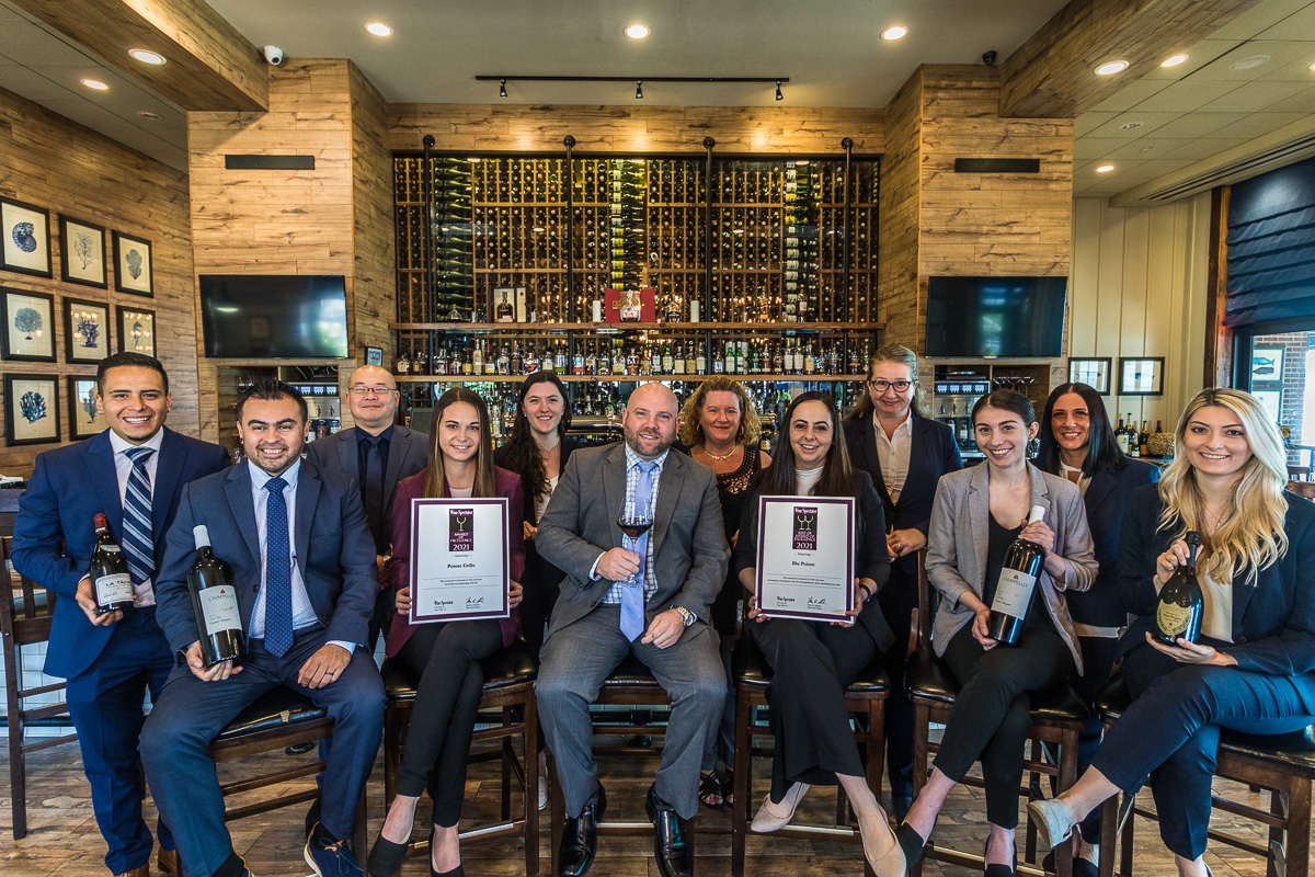 Blu Pointe team in 2021 posing with Wine Spectator Best of Award of Excellence in front of the bar